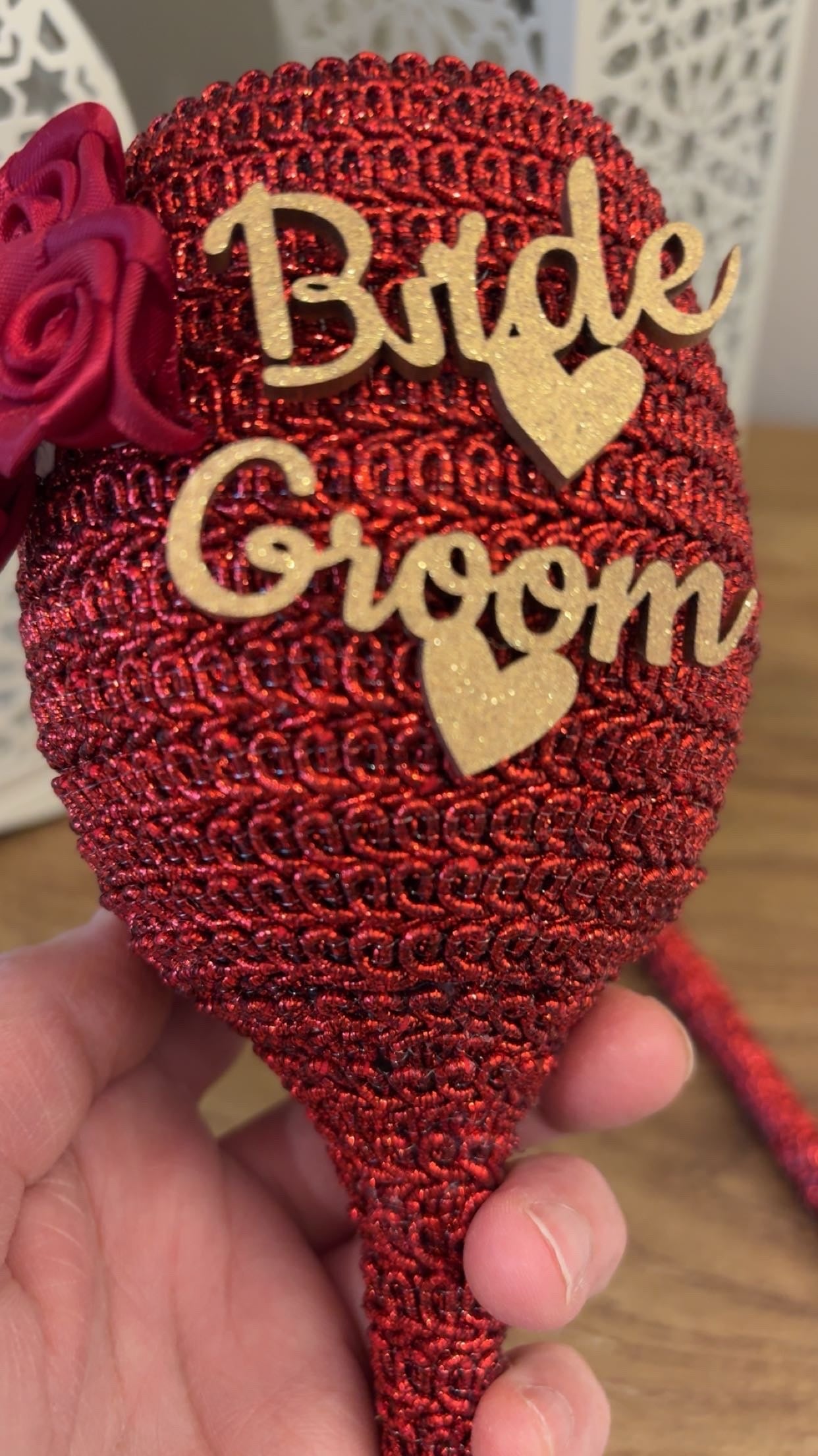 Decorative brooch with 'Bride' and 'Groom' text on a red background